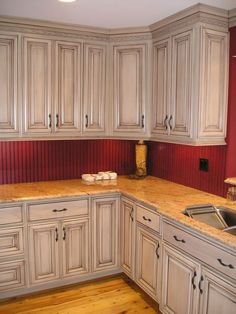 a kitchen with white cabinets and wood floors is shown in this advertisement for the kitchen cabinets click below