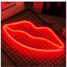 a red neon sign sitting on top of a metal grate next to a window