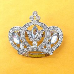 a crown brooch sitting on top of a yellow surface