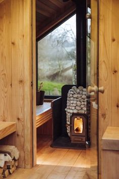 a wood burning stove sitting inside of a wooden cabin next to a bench and window