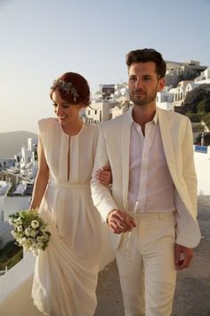 a man and woman are walking down the street together, dressed in all white attire