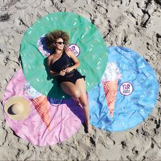 a woman laying on top of an inflatable ice cream cone covered beach towel