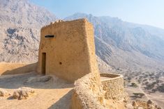 an adobe building in the desert with mountains in the background