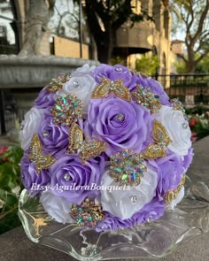 purple and white bridal bouquet with butterfly brooches on glass stand in front of flowers