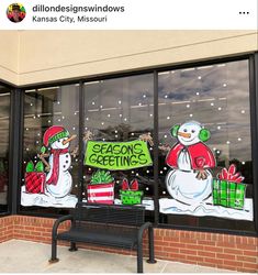 a storefront with christmas decorations and snowmen painted on the glass windows, along with a bench