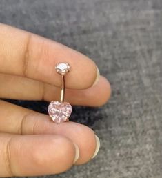 a person's hand holding an engagement ring with a heart shaped diamond on it