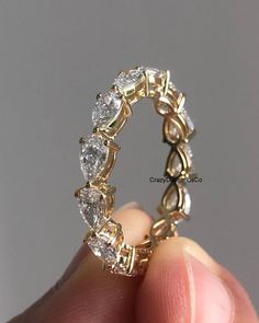 a person holding up a gold ring with three diamonds on it's sides and the middle