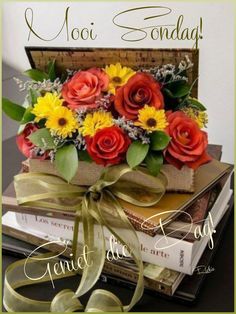 a box filled with flowers sitting on top of a table next to a ribbon tied around it