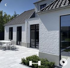 an outdoor patio with tables and chairs next to a white brick building on a sunny day