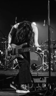 a man with long hair playing guitar on stage