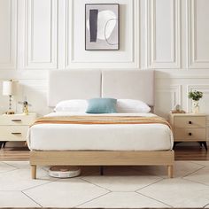 a bedroom with white walls and wood furniture, including a large bed that has two nightstands next to it