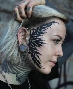 a woman with tattoos on her face and behind her ear