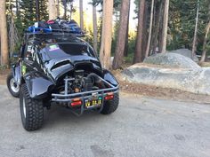 a black motorcycle parked on the side of a road next to some trees and rocks