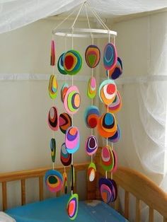 a mobile with circles hanging from it's side on a bed in a child's room