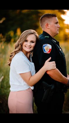 a man and woman hugging each other in front of a police officer