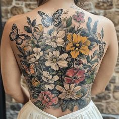 the back of a woman's body with flowers and butterflies on it