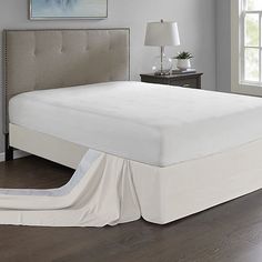 a bed that has been made and is in the middle of a room with hardwood floors