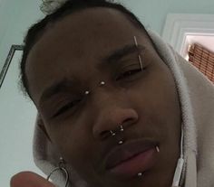 a man with piercings on his nose wearing a hoodie