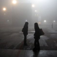 two people standing in the middle of an empty parking lot on a foggy day