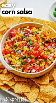 corn salsa in a white bowl surrounded by tortilla chips on a platter