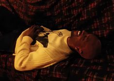 a young man laying on top of a couch holding a remote control in his hand