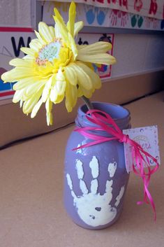 a painted vase with a flower in it and a handprint on the inside is shown