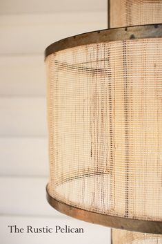 a lamp hanging from the side of a wooden pole with a woven shade on it