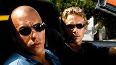 two men sitting in the back seat of a car, one with sunglasses on his head