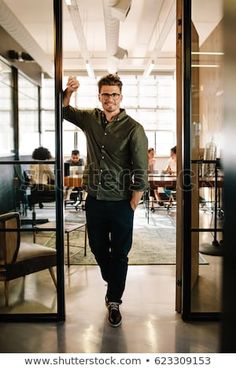 a man walking through an open door to another room with chairs and desks in the background