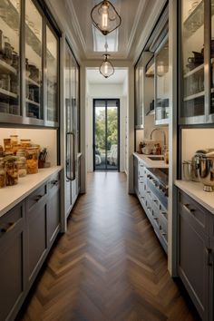 a long narrow kitchen with wood flooring and stainless steel appliances on either side of the door