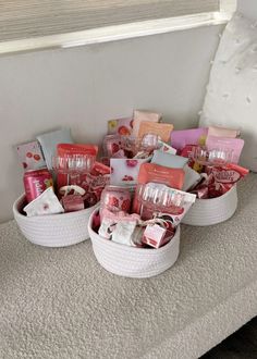 two baskets filled with various items on top of a bed next to a window sill