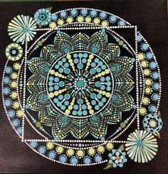 a painting with blue, green and yellow designs on black paper next to a wooden table