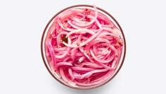 a bowl filled with sliced red onions on top of a white table