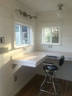 an empty room with two windows and a desk in the corner on top of it