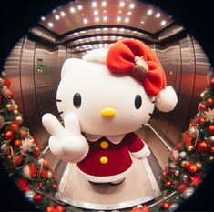 a hello kitty doll is standing in front of a christmas wreath with lights on it