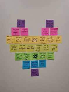 post it notes arranged in the shape of a heart on a white wall with words written all over them