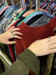 a woman's hand reaching for a ring on top of a rack of clothes