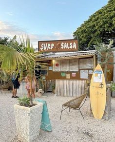 people are standing in front of a surf shop with a yellow surfboard next to it