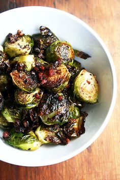 a black bowl filled with potatoes and broccoli on top of a wooden table