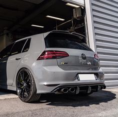 the rear end of a white car parked in front of a garage