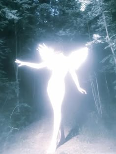 a woman with her arms spread out in the air while standing on a path surrounded by trees