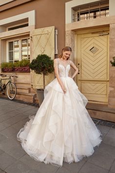 a woman in a wedding dress standing on the sidewalk