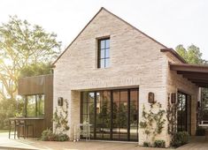 a brick house with glass doors and windows on the outside, surrounded by greenery