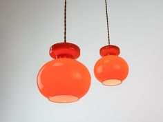 two orange light bulbs hanging from a ceiling