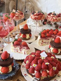 many desserts are displayed on plates with strawberries