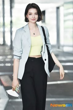 a woman in black pants and a yellow top is walking down the street with her hand on her hip