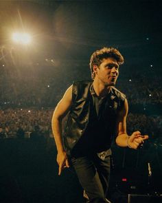 a man standing on top of a stage in front of a crowd at a concert