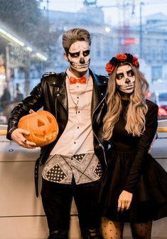 a man and woman dressed up as skeletons holding jack - o'- lantern pumpkins