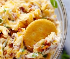 a glass bowl filled with pasta salad and a cracker on the side next to some lemons