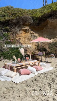 a picnic on the beach with pink and white pillows